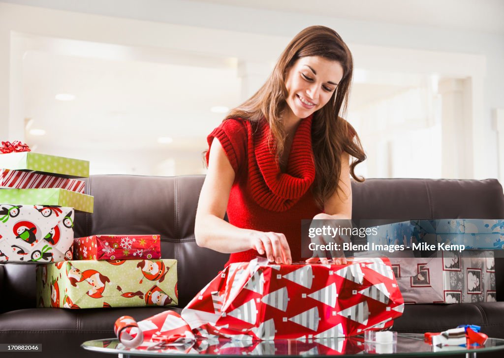 Caucasian woman wrapping Christmas presents in living room