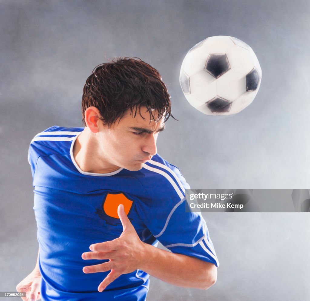 Hispanic soccer player hitting ball with head