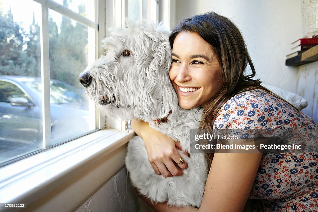 Caucasian woman hugging dog at window