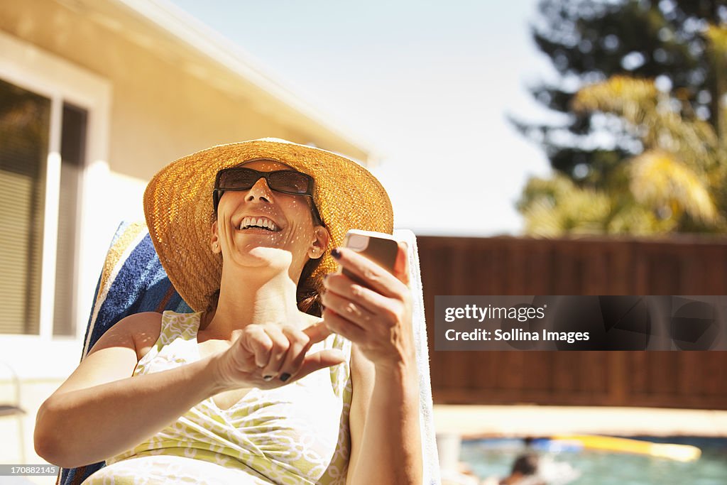 Hispanic woman using cell phone by pool