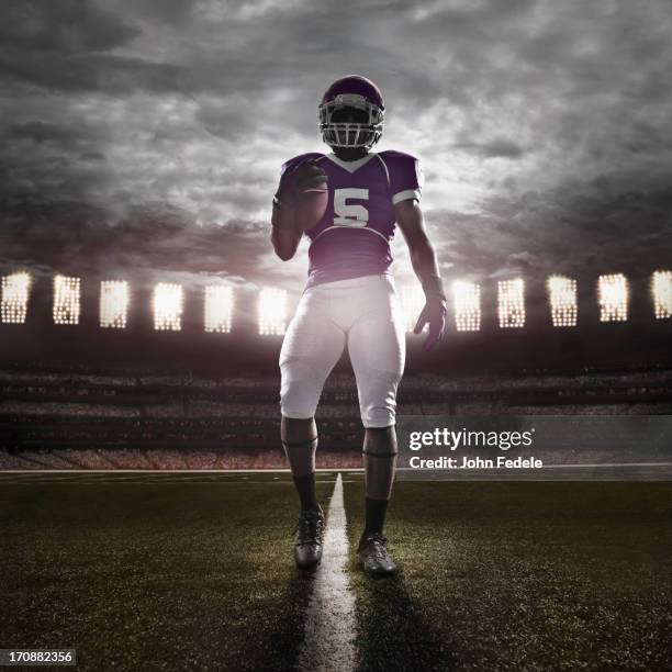 african american football player illuminated on field - football spieler stock-fotos und bilder