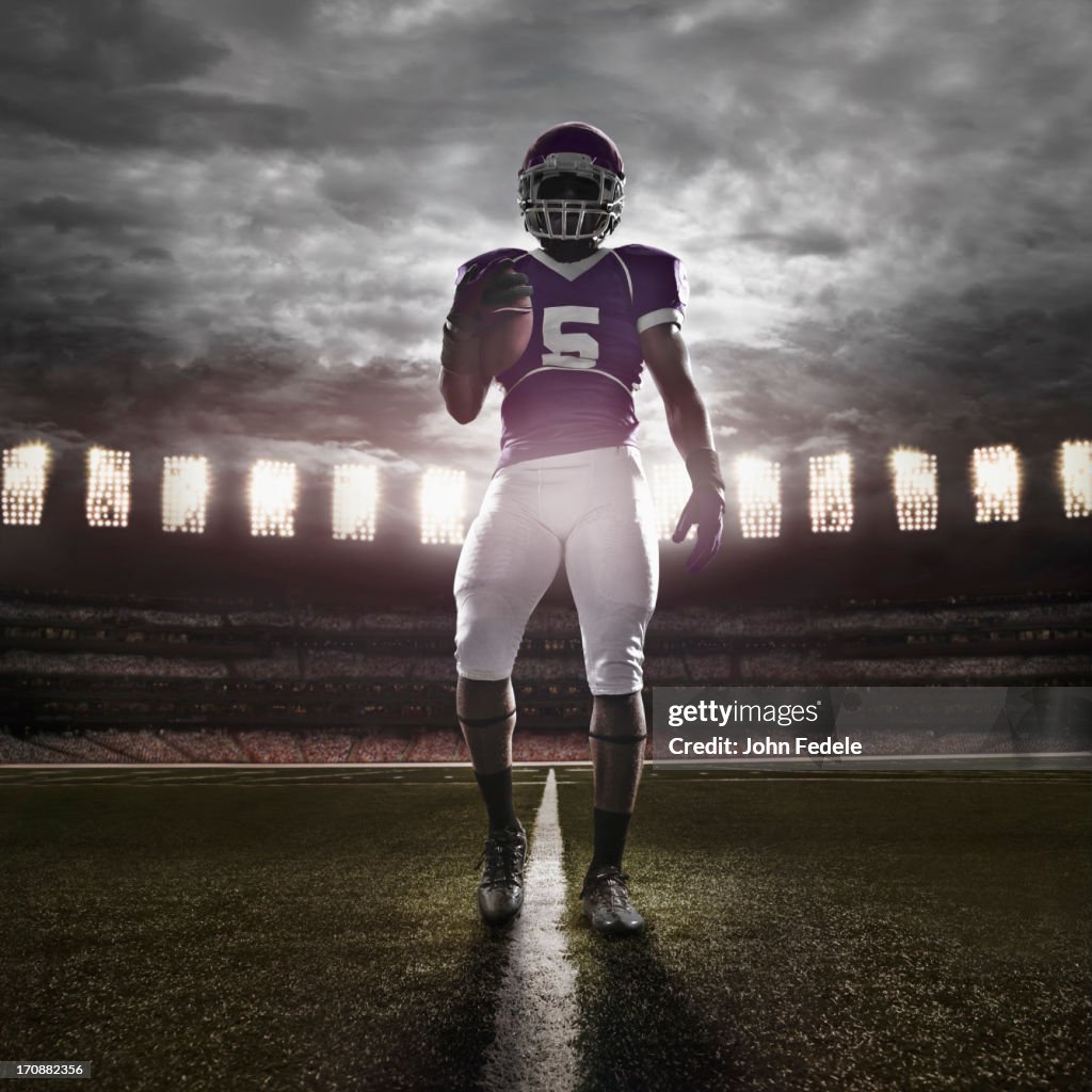 African American football player illuminated on field