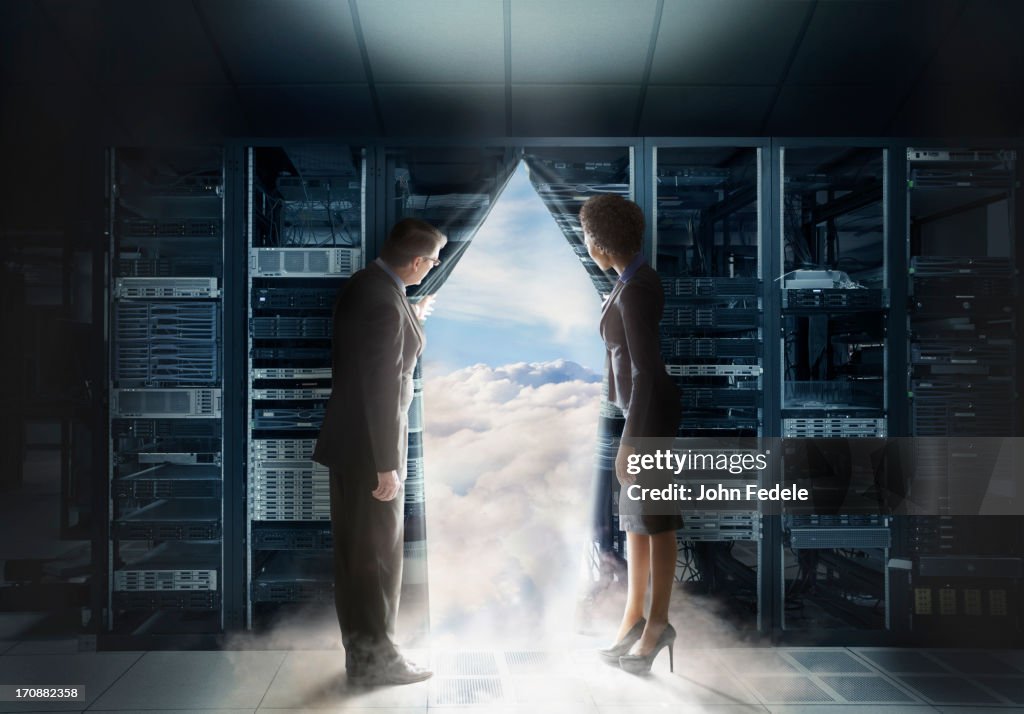 Business people pulling back curtain to clouds