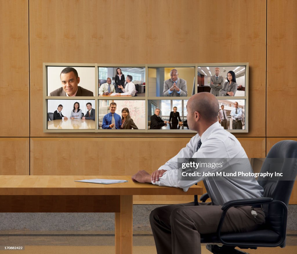 Businessman watching collage screen in office