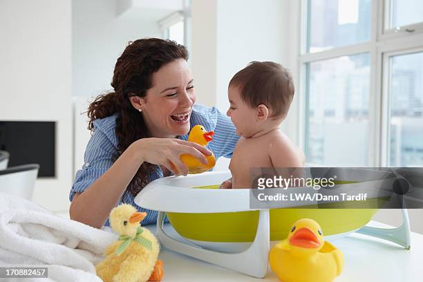 mother bathing baby on counter top - baby bath toys stock pictures, royalty-free photos & images
