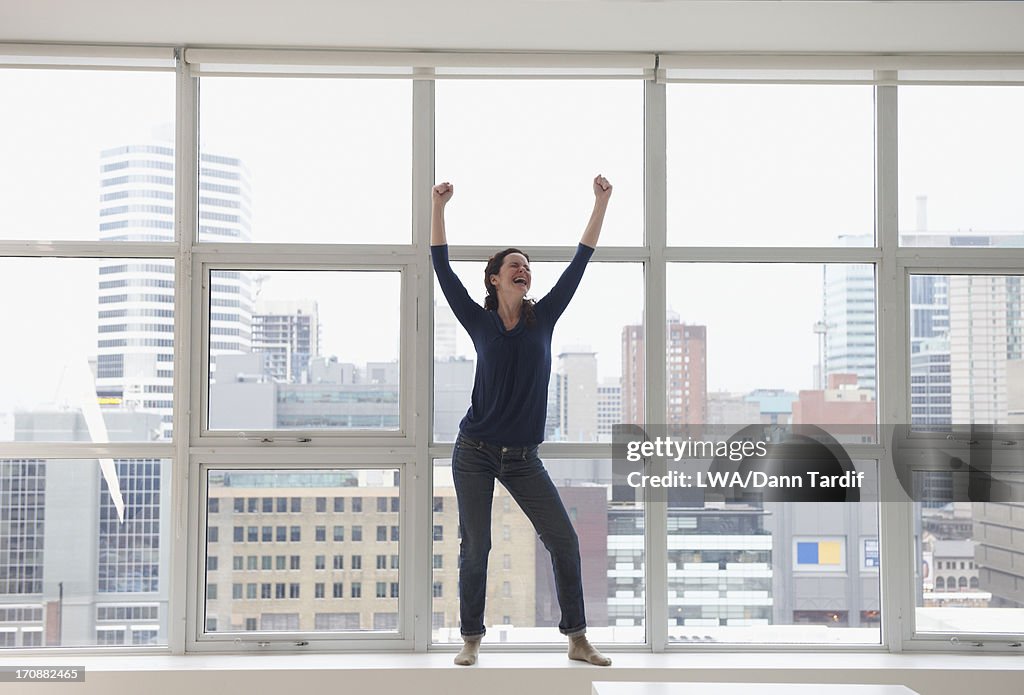 Caucasian businesswoman standing on windowsill