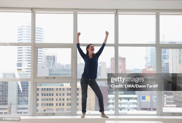 caucasian businesswoman standing on windowsill - frau arme hoch ganzkörper stock-fotos und bilder