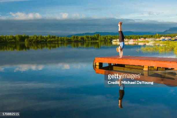caucasian woman practicing yoga on dock on still lake, anchorage, alaska, united states - アンカレッジ ストックフォトと画像