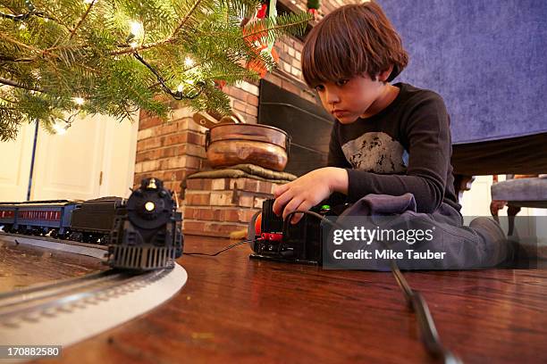 mixed race boy playing with train under christmas tree - six under ストックフォトと画像