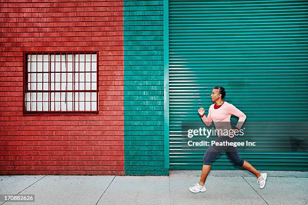 black woman running on city street - active lifestyle los angeles stock-fotos und bilder