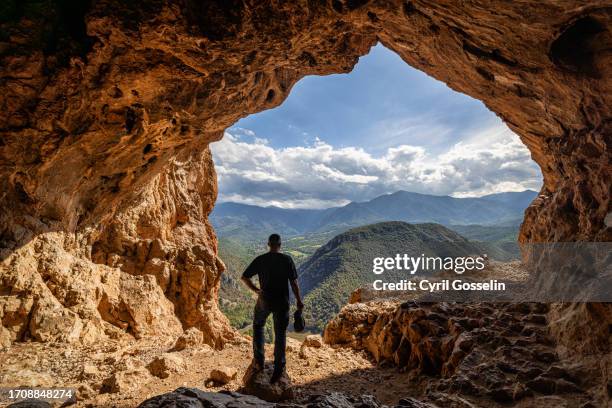 man standing in cavern, looking at mountain landscape - villefranche de conflent photos et images de collection