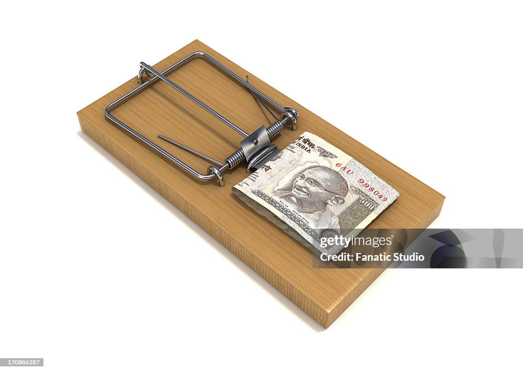 Conceptual shot of paper currency placed on mouse trap over white background