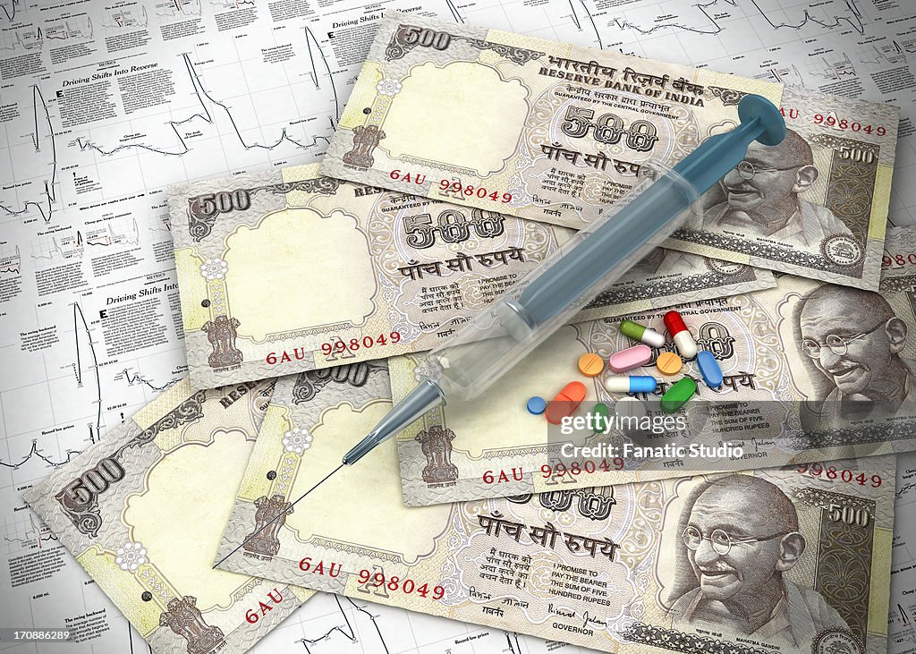 Paper currency with medicines and syringe on chart representing investment in stock market