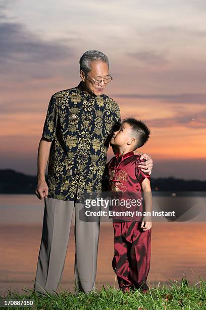 grandfather looking at grandson at sunset - generationsunterschied stock-fotos und bilder