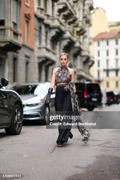 Guest wears earrings, a light grey with a black floral pattern chiffon crop top with American armholes, a matching vaporous long bow at the waist,...