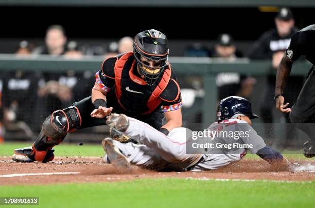 Ceddanne Rafaela of the Boston Red Sox scores in the ninth inning ahead of the tag of James McCann of the Baltimore Orioles at Oriole Park at Camden...