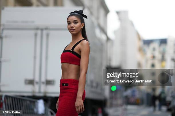 Guest wears a ribbon over the hair, a black and red crop top / bras made of tweed, a long tweed skirt, outside Alessandra Rich, during the Womenswear...