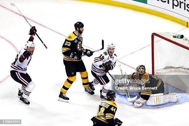 Bryan Bickell and Jonathan Toews of the Chicago Blackhawks celebrate after Brent Seabrook k scores the game winning goal against Tuukka Rask of the...