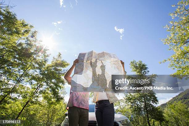 couple examine road map near car, in forest - stappenplan stockfoto's en -beelden