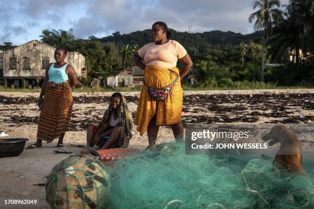 Woman wait to buy fish from a pirogue in Robertsport on October 5, 2023. Surfing in the fishing town of Robertsport has taken off in the last years,...