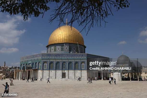 Palestinians walk past the Dome of the Rock at the Al-Aqsa Mosque compound, Islam's third holiest site, ahead of Friday prayers in the Old City of...