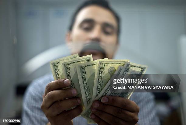 An Indian moneychanger counts US Dollar bills at his office in New Delhi on June 20, 2013. India's rupee hit a new low against the US Dollar after...