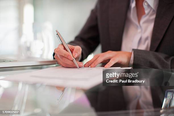 geschäftsfrau schreiben auf papier am schreibtisch - documents stock-fotos und bilder