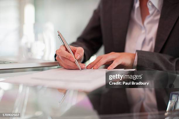 businesswoman writing on paper at desk - contrat stock pictures, royalty-free photos & images