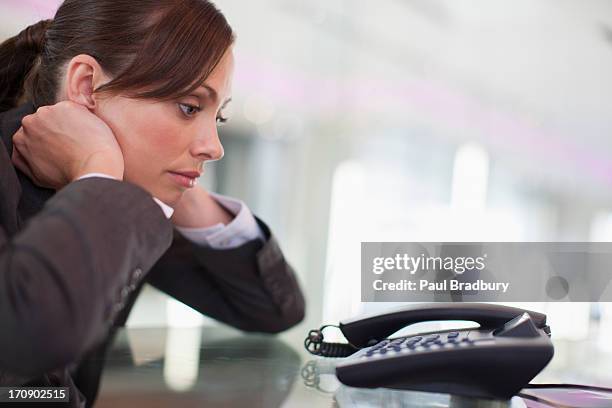 businesswoman staring at telephone waiting for it to ring - waiting phone stock pictures, royalty-free photos & images