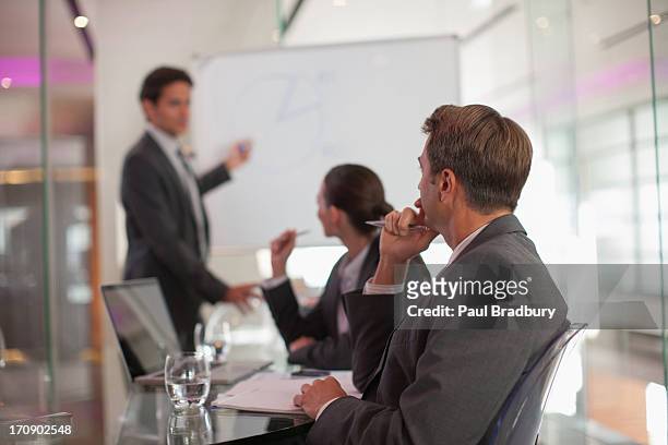 businessman talking to co-workers in conference room - co presented stockfoto's en -beelden