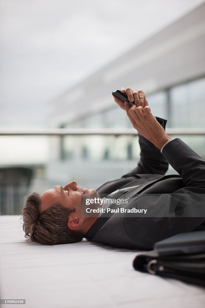 Businessman laying and using cell phone in office