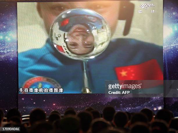 Chinese female astrounaut Wang Yaping is reflected in a drop of water floating in Tiangong-1 space module as she delivers a lesson to students that...