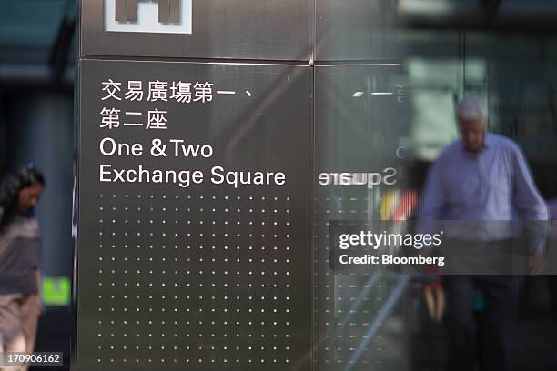 Man is reflected in glass next to signage for Exchange Square towers One and Two, which house companies such as the Hong Kong Exchanges and Clearing...