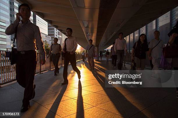 Pedestrians walk on an overpass during sunset in the business district of Central in Hong Kong, China, on Wednesday, June 19, 2013. Chief Executive...