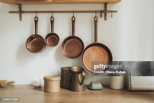 copper stewpans above kitchen table with utensils. - handle stock-fotos und bilder