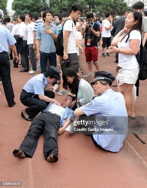 An injured police officer receives assistance after being caught in a crush of people as David Beckham arrived at Tongji University on June 20, 2013...