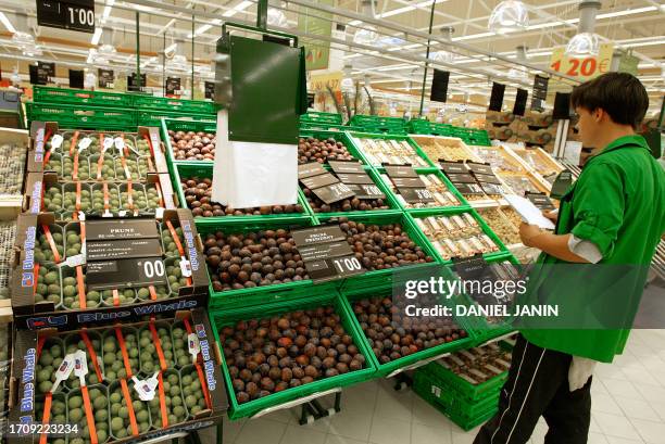 Vue prise le 27 août 2002 à Sénart, d'un employé du supermarché Carrefour vérifiant le rayon des fruits, dans le centre commercial géant de 65.000...