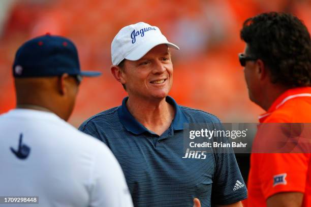 Assistant coach Major Applewhite of the South Alabama Jaguars talks with head coach Mike Gundy of the Oklahoma State Cowboys before their game at...