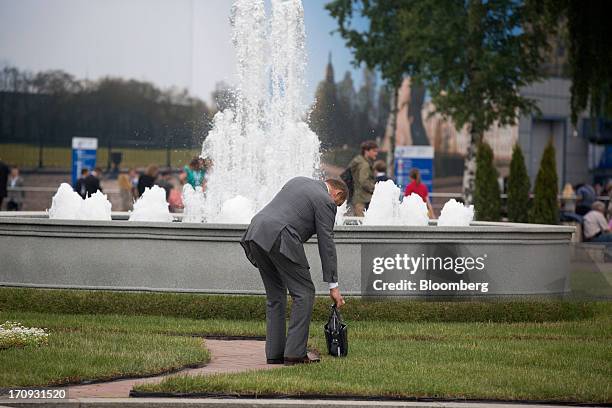 Business executive pauses beside a water fountain in the main square on the opening day of the St. Petersburg International Economic Forum 2013 in...