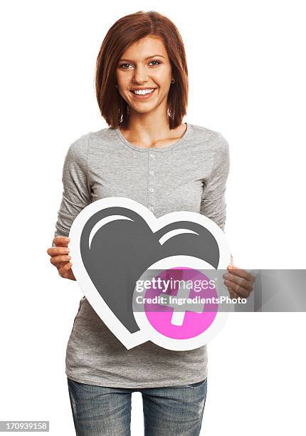 lächelnde junge frau hält herz-symbol isoliert auf weißem hintergrund - plus zeichen stock-fotos und bilder