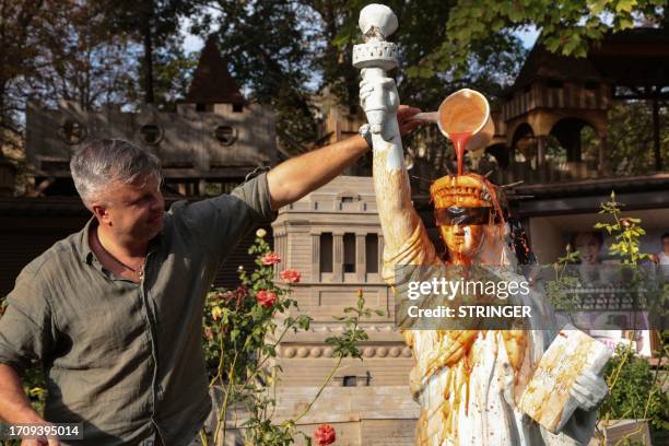 Local resident pours juice on the replica of the Statue of Liberty as it is removed from an amusement park as a protest against US policy in...