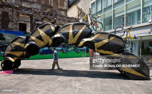 Man walks next to the sculpture "Sobreponiendose" -part of the "A vuelta de rueda" exhibition- of Mexican artist Betsabee Romero, on March 24, 2009...