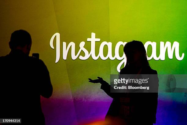 George Sylvain, left, takes a photograph of Tara Shi while standing in front of the Instagram Inc. Logo during an event at Facebook Inc. Headquarters...