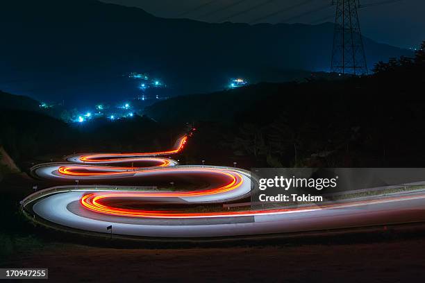 light trails of cars on the zigzag way - fanale posteriore foto e immagini stock