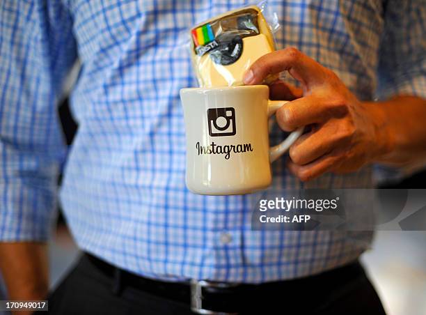 An employee holds a cup with the Instagram logo at Facebook's corporate headquarters during a media event in Menlo Park, California, on June 20,...