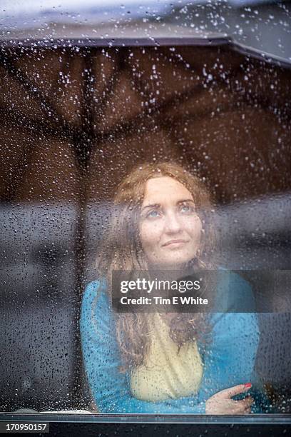 woman inside looking at the rain on a window - window rain stock pictures, royalty-free photos & images