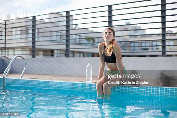 young woman in workout clothes, feet in the pool - knöcheltief im wasser stock-fotos und bilder