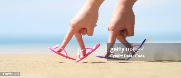 two hands with flip flops on fingers on beach - persoonlijk accessoire stockfoto's en -beelden
