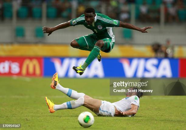 Joseph Akpala of Nigeria jumps a tackle from Martin Caceres of Uruguay during the FIFA Confederations Cup Brazil 2013 Group B match between Nigeria...