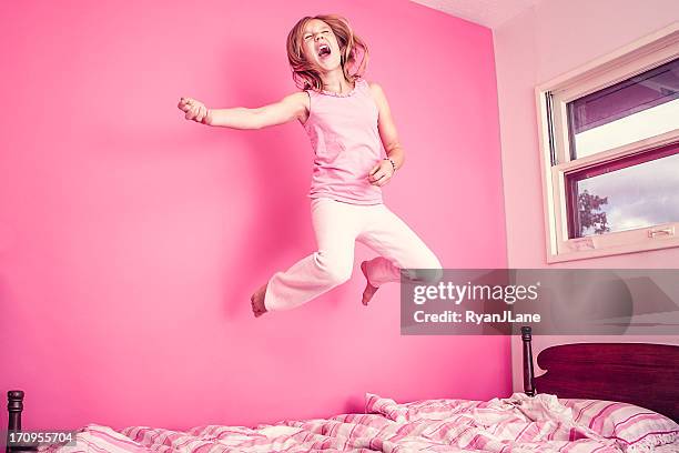 mädchen springen auf dem bett in rosa zimmer - children jumping bed stock-fotos und bilder